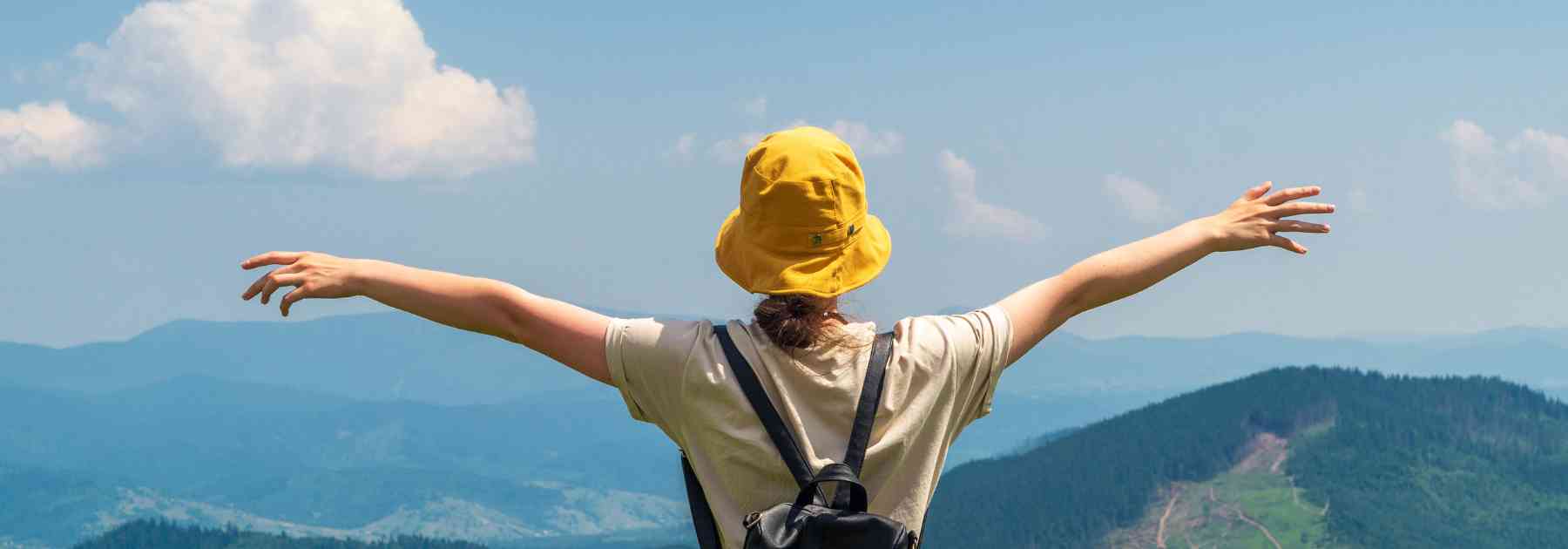 person wearing yellow hat looking at mountains